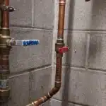 Copper plumbing pipes with shutoff valves on wall