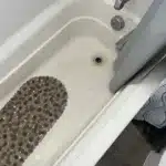 Stained bathtub with bath mat and shower curtain
