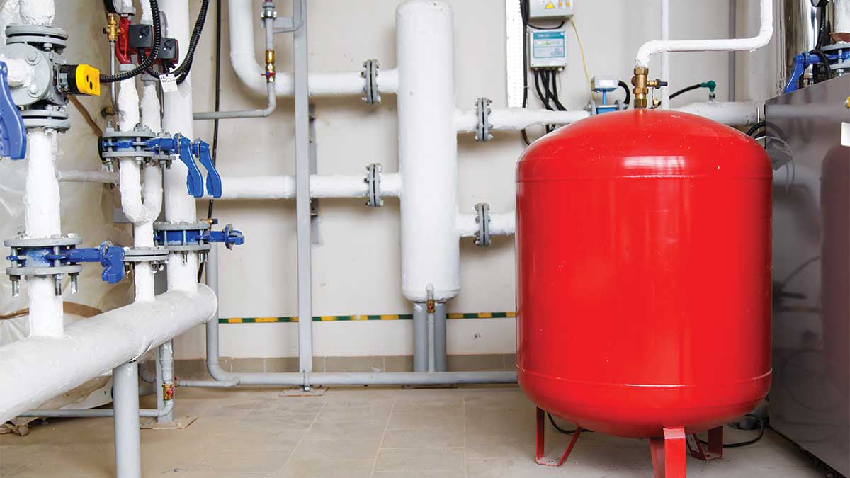 Industrial valves and a red pressure tank installed within a boiler system, showing the components of a boiler expansion tank setup. Image used for Cardom Plumbing & Heating’s guide on Boiler Expansion Tanks, highlighting system pressure management and essential plumbing hardware.