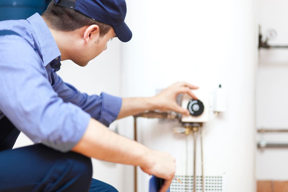 Cardom Plumbing & Heating technician adjusting water heater settings – expert service for boilers in Arvada homes and businesses.