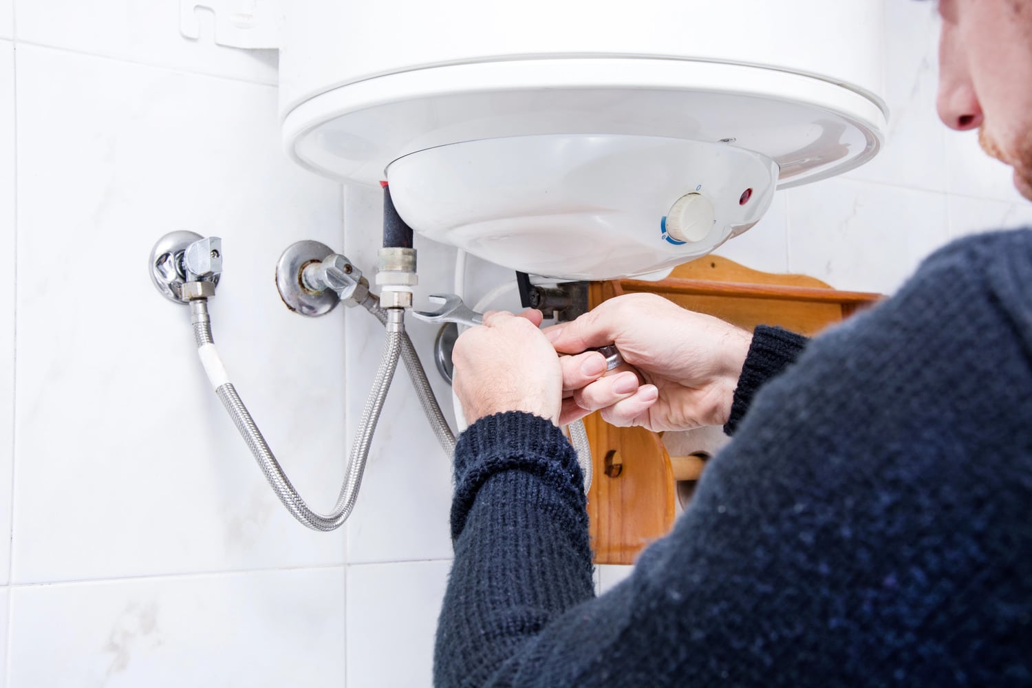 Cardom Plumbing and Heating fixes Common Water Heater Issues. A plumber repairs a water heater with a wrench to ensure efficient performance.