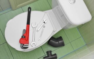 Plumbing tools on toilet lid, ready for repair.