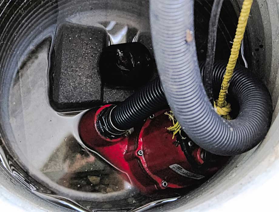 Submersible pump installed in a sump pit with standing water, efficiently removing excess water to prevent flooding. Cardom Plumbing & Heating offers expert Sump Pump Services in Arvada to keep your basement dry and protected from water damage.