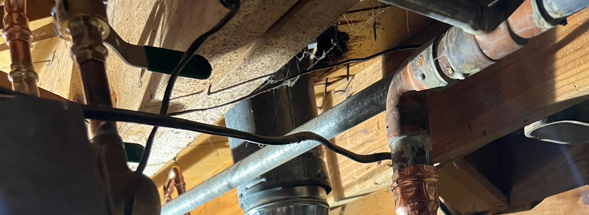 Rusty pipes and wires in basement ceiling